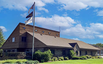A flag pole with two flags on top of a building. AI generated content